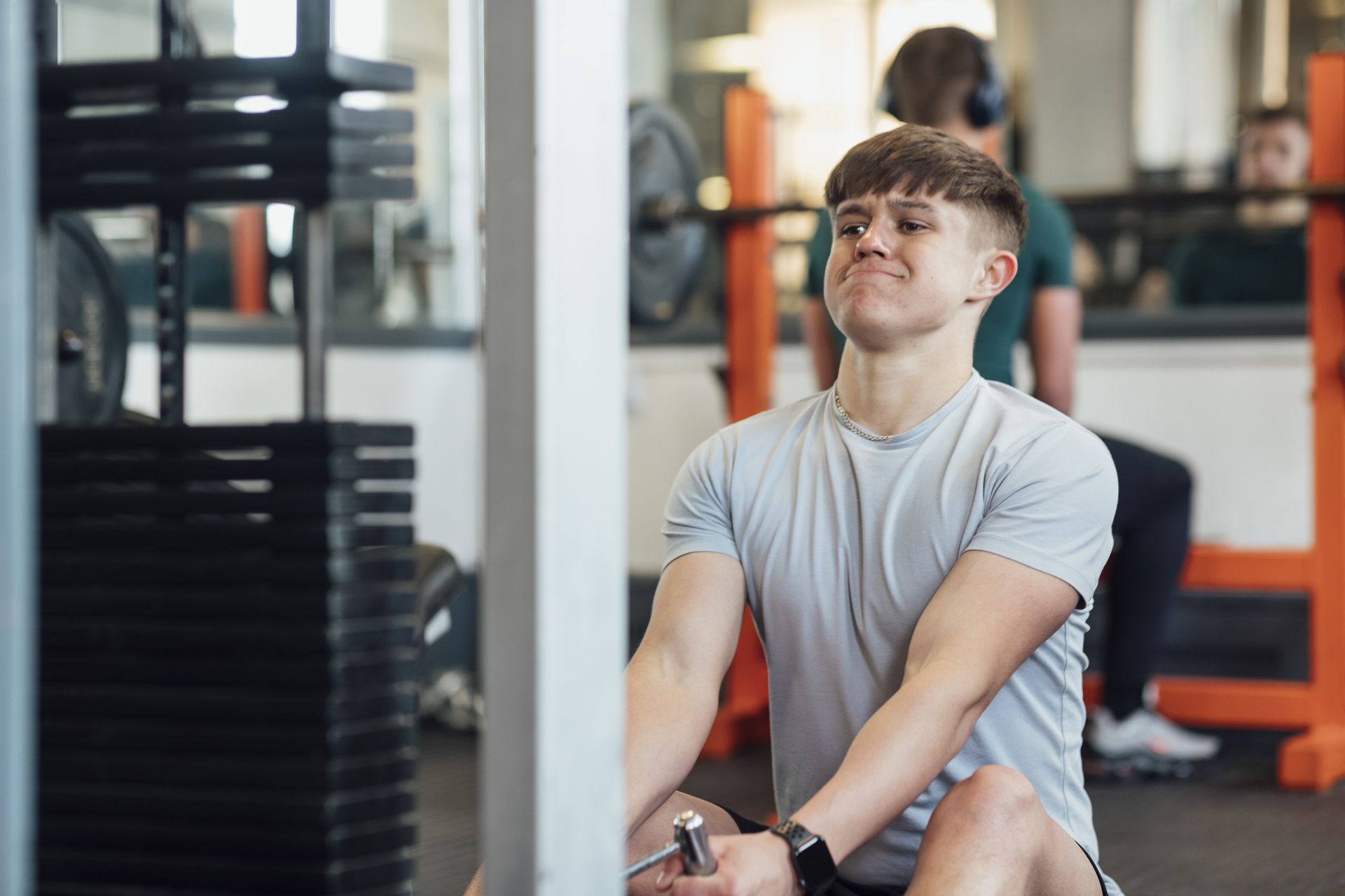 A teenager works through a seated cable exercise in a weight room.
